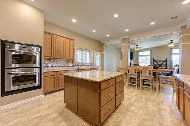 kitchen featuring sink, light stone countertops, tasteful backsplash, a kitchen island, and stainless steel appliances