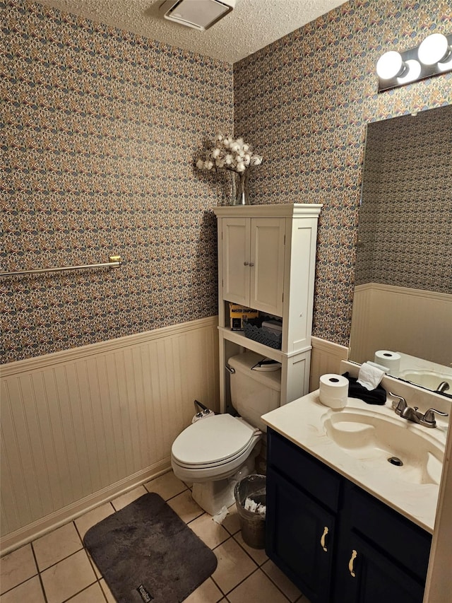 bathroom featuring tile patterned floors, vanity, a textured ceiling, wooden walls, and toilet