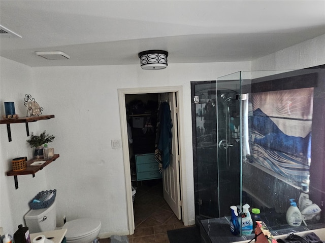 bathroom with tile patterned floors, toilet, and a shower with shower door