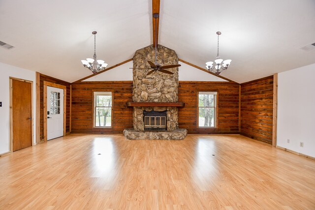 unfurnished living room with a stone fireplace, wooden walls, a healthy amount of sunlight, and light wood-type flooring