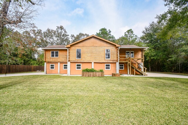 rear view of house featuring a wooden deck and a yard