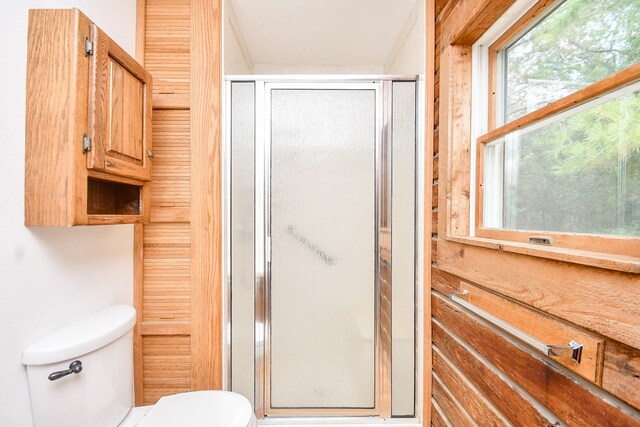 bathroom with a shower with shower door and toilet