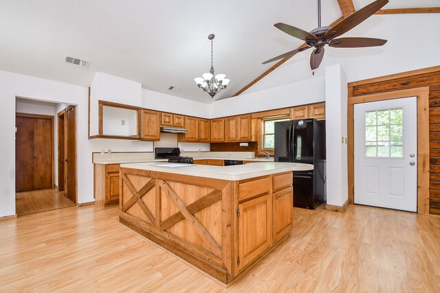 kitchen featuring light wood-type flooring, black appliances, decorative light fixtures, high vaulted ceiling, and a kitchen island