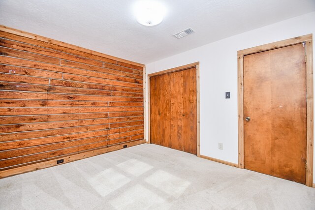 unfurnished bedroom with a textured ceiling, light colored carpet, and a closet