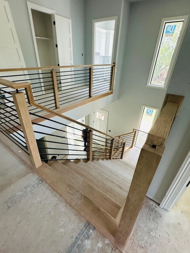 stairs with hardwood / wood-style floors and a high ceiling