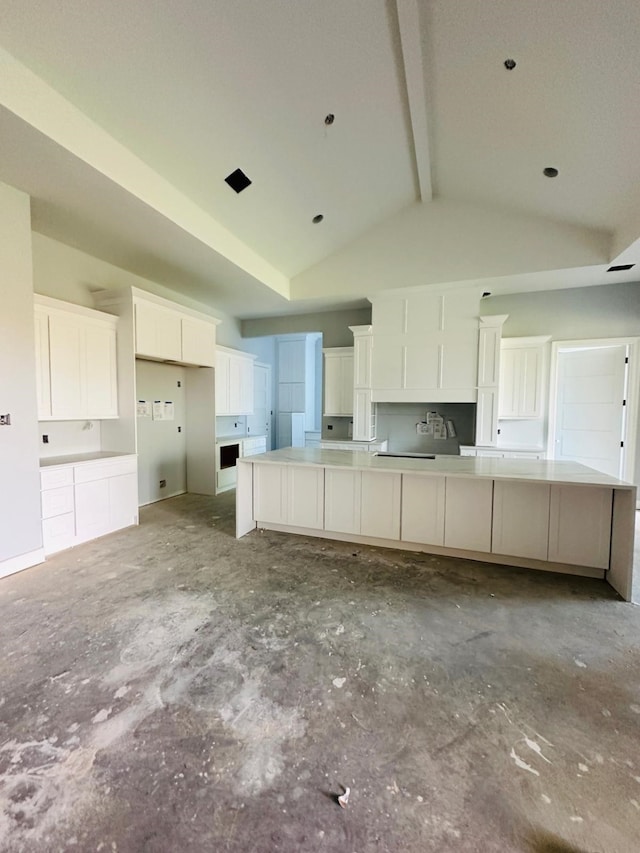 kitchen featuring a large island, vaulted ceiling with beams, and white cabinetry