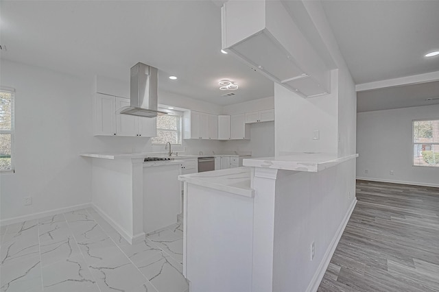 kitchen with kitchen peninsula, white cabinetry, island exhaust hood, and stainless steel dishwasher