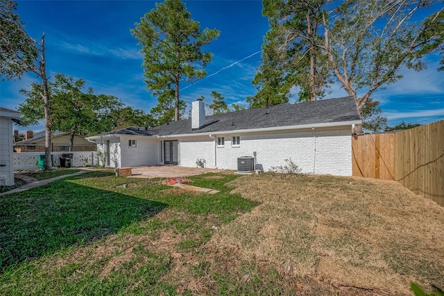 back of property with a patio, central air condition unit, and a lawn