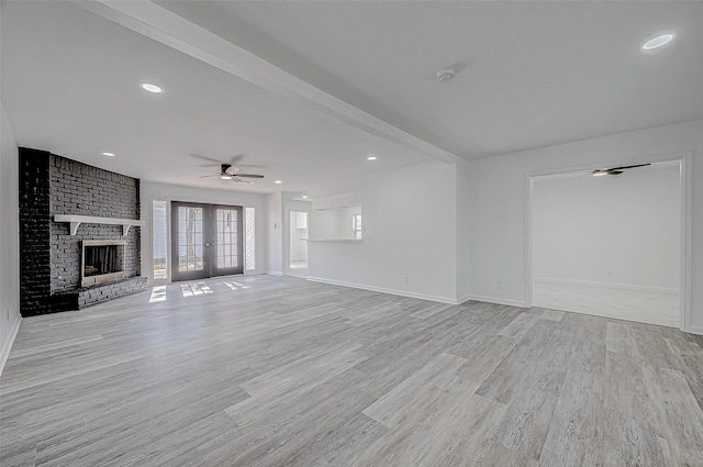 unfurnished living room featuring a fireplace, ceiling fan, french doors, and light hardwood / wood-style floors