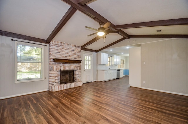 unfurnished living room featuring lofted ceiling with beams, sink, a brick fireplace, ceiling fan, and dark hardwood / wood-style flooring