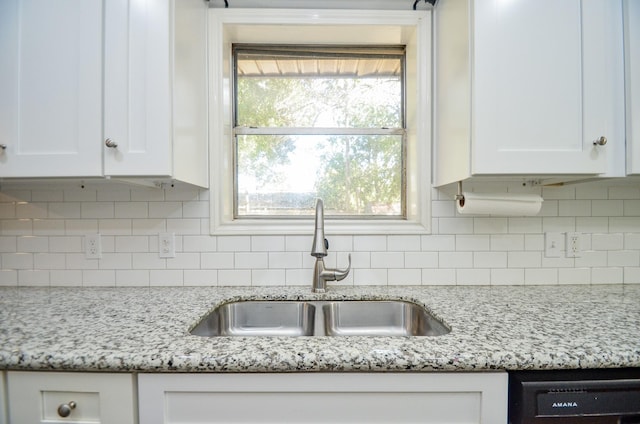 kitchen featuring backsplash, light stone countertops, sink, and white cabinets