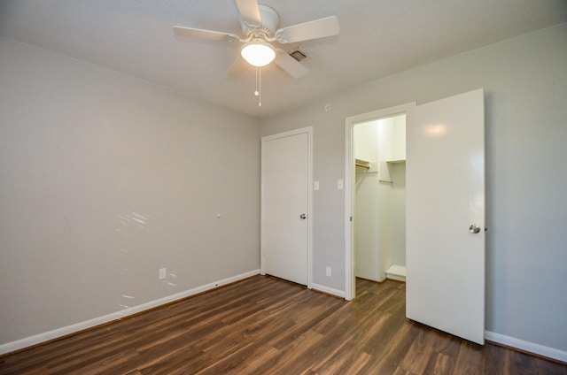 unfurnished bedroom with ceiling fan, dark hardwood / wood-style flooring, a walk in closet, and a closet