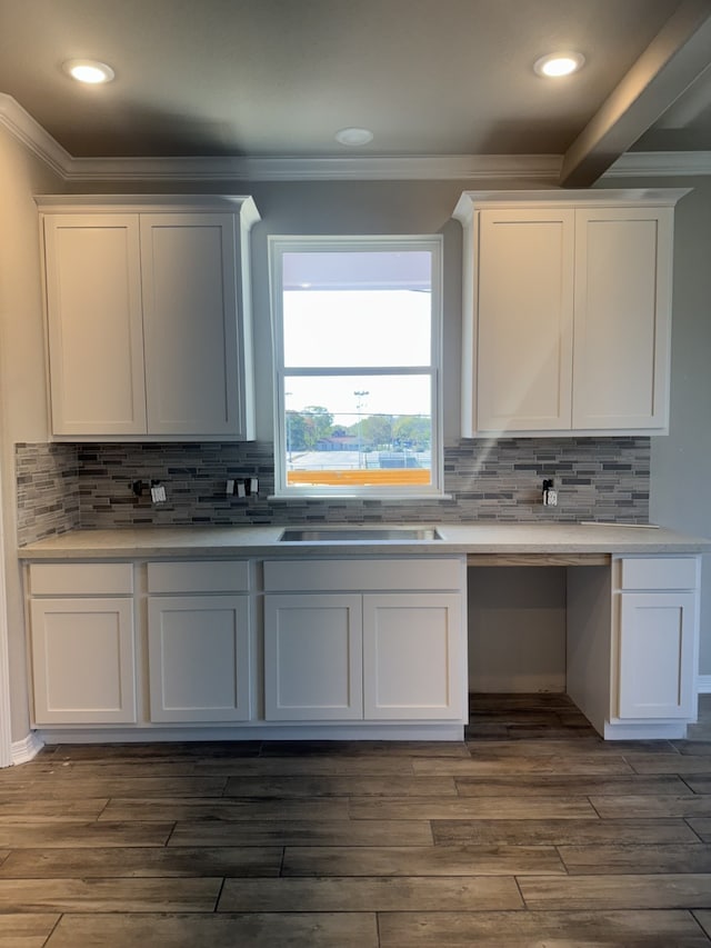 kitchen featuring dark hardwood / wood-style flooring, tasteful backsplash, crown molding, sink, and white cabinetry