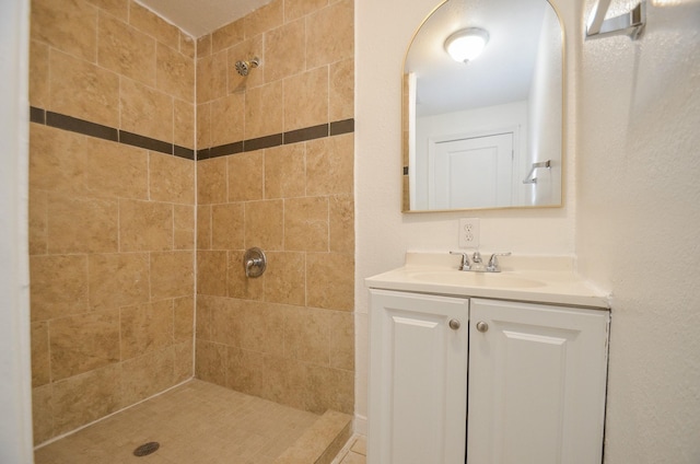 bathroom with tiled shower and vanity