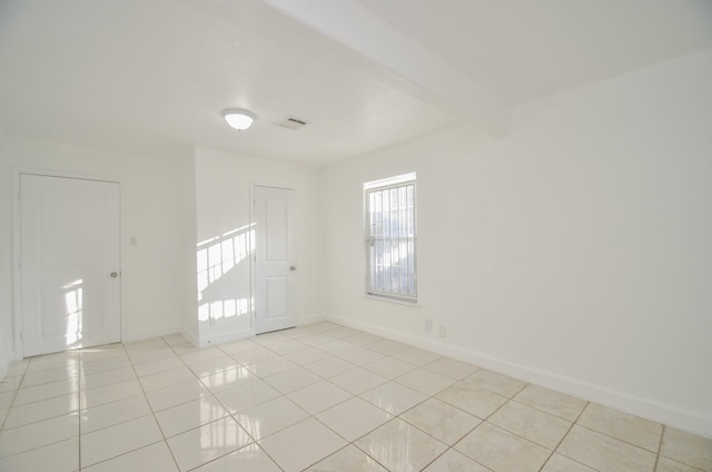 tiled spare room with beamed ceiling