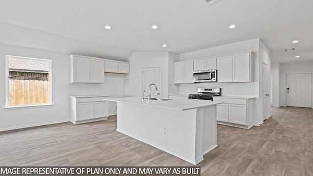 kitchen featuring white cabinets, sink, stainless steel appliances, and an island with sink