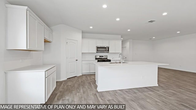 kitchen featuring a kitchen island with sink, sink, light wood-type flooring, white cabinetry, and stainless steel appliances