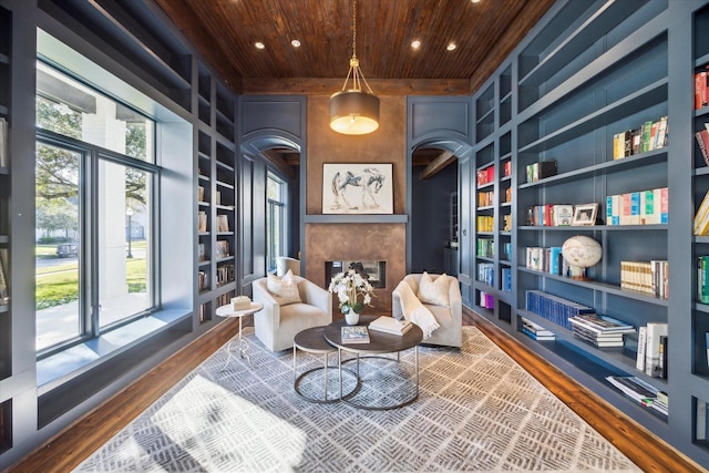 sitting room with hardwood / wood-style flooring, built in shelves, wood ceiling, and a premium fireplace