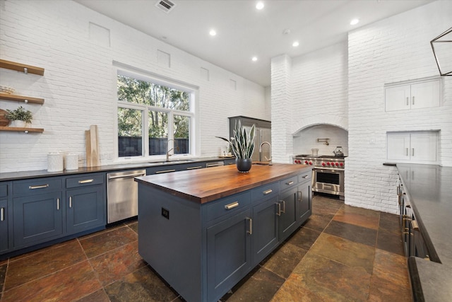 kitchen with blue cabinetry, sink, stainless steel appliances, and wooden counters