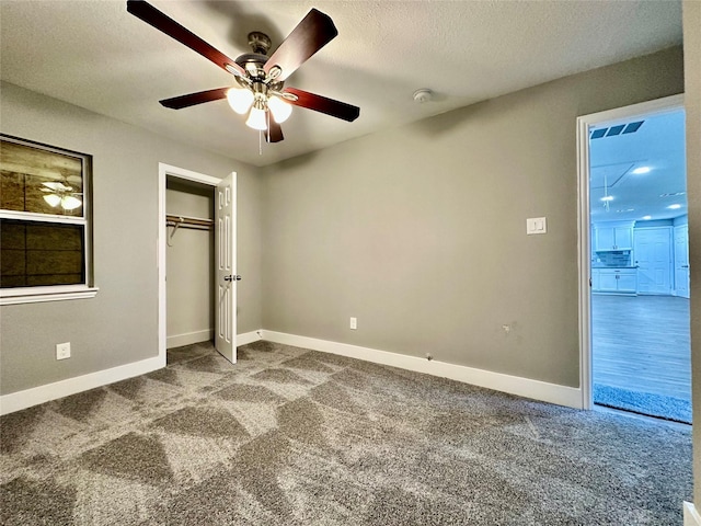 unfurnished bedroom featuring carpet flooring, a textured ceiling, a closet, and ceiling fan