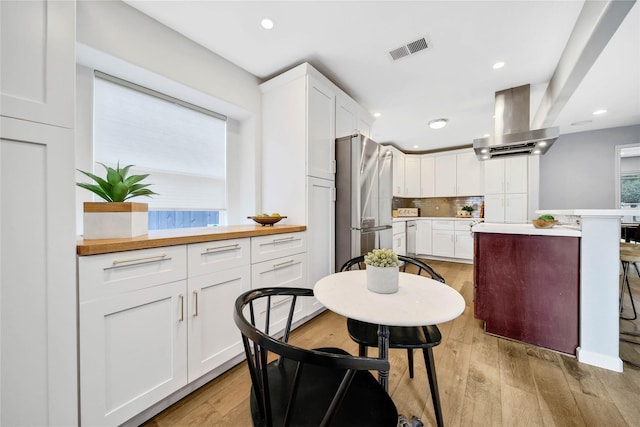 kitchen with white cabinets, island range hood, and light hardwood / wood-style floors