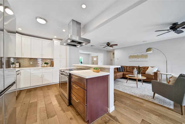 kitchen with electric range, backsplash, island range hood, white cabinets, and light wood-type flooring