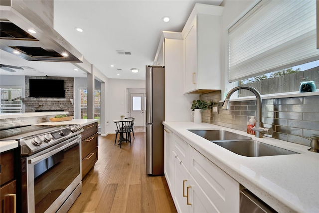 kitchen featuring white cabinets, range hood, sink, and appliances with stainless steel finishes