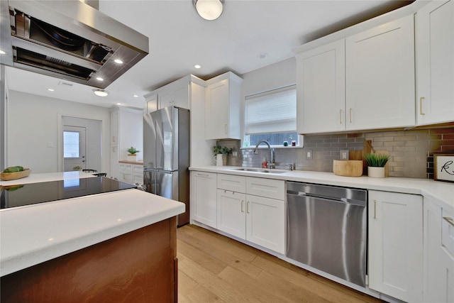 kitchen featuring white cabinets, appliances with stainless steel finishes, extractor fan, and a wealth of natural light