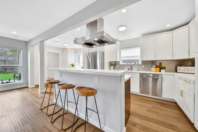 kitchen with a healthy amount of sunlight, island range hood, white cabinets, and stainless steel appliances