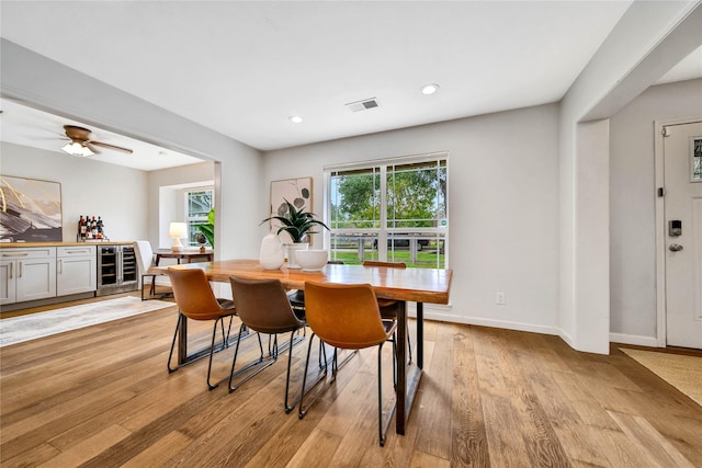 dining space featuring ceiling fan, light hardwood / wood-style floors, and beverage cooler