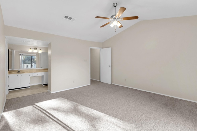 unfurnished bedroom featuring ceiling fan, sink, light carpet, and vaulted ceiling