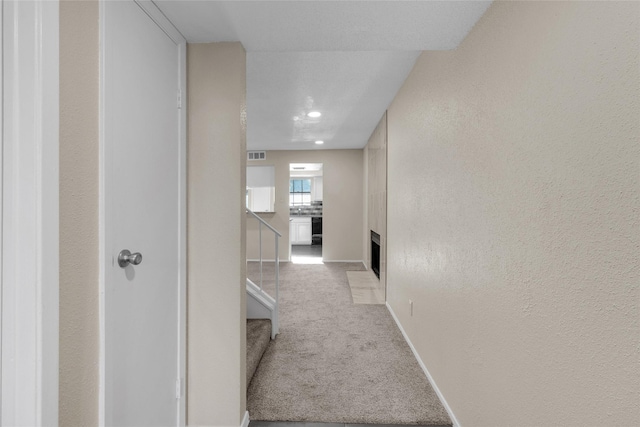 hallway featuring light carpet and a textured ceiling