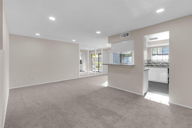 unfurnished living room with light colored carpet and sink