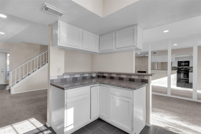 kitchen with dark carpet, kitchen peninsula, a textured ceiling, white cabinets, and black appliances