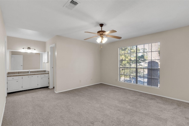 unfurnished bedroom featuring ensuite bath, ceiling fan, and light colored carpet