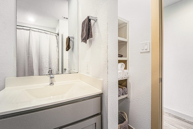 bathroom with a shower with shower curtain, hardwood / wood-style floors, and vanity