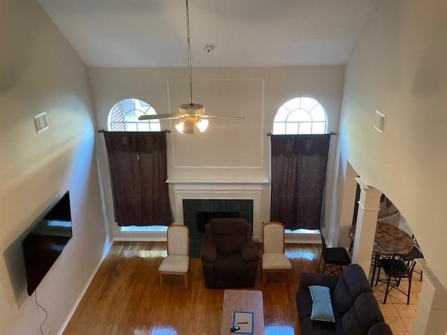 living room with a fireplace, ceiling fan, hardwood / wood-style floors, and a high ceiling