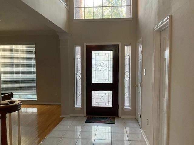 foyer featuring a high ceiling, light wood-type flooring, and a healthy amount of sunlight