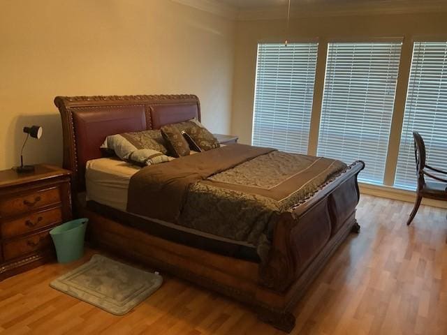 bedroom with hardwood / wood-style flooring, ornamental molding, and multiple windows