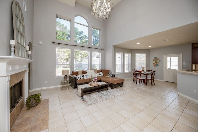 tiled living room featuring a tiled fireplace, a high ceiling, and an inviting chandelier