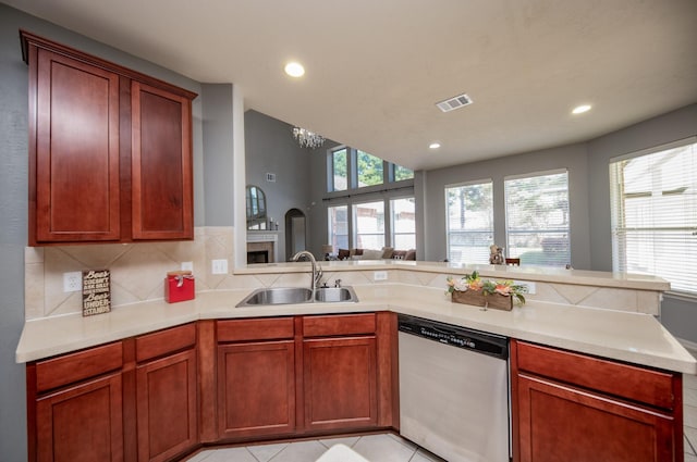 kitchen with dishwasher, sink, decorative backsplash, light tile patterned floors, and a chandelier