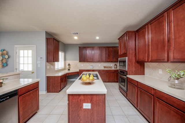 kitchen with tasteful backsplash, a center island, light tile patterned floors, and appliances with stainless steel finishes