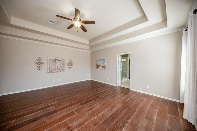 empty room featuring dark hardwood / wood-style flooring, ceiling fan, a raised ceiling, and crown molding