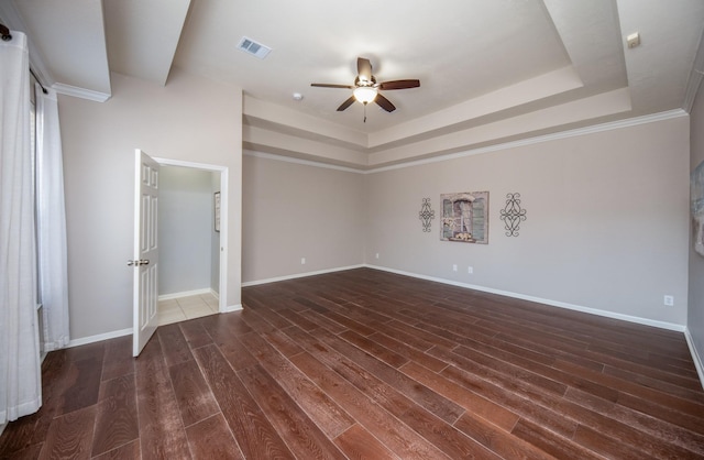 unfurnished bedroom featuring a raised ceiling, ceiling fan, dark hardwood / wood-style flooring, and ornamental molding