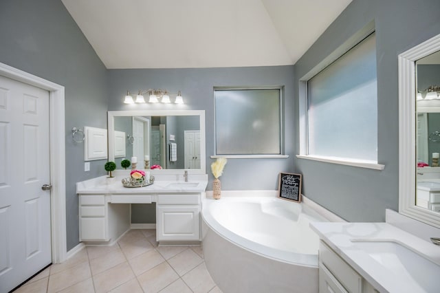 bathroom with a bathtub, vanity, vaulted ceiling, and tile patterned flooring