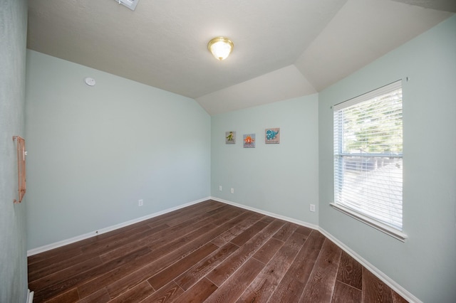 empty room with dark hardwood / wood-style floors and vaulted ceiling