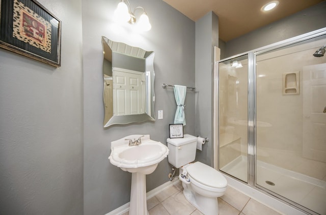 bathroom with tile patterned floors, toilet, and a shower with door