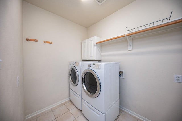 washroom with washer and dryer, cabinets, and light tile patterned floors