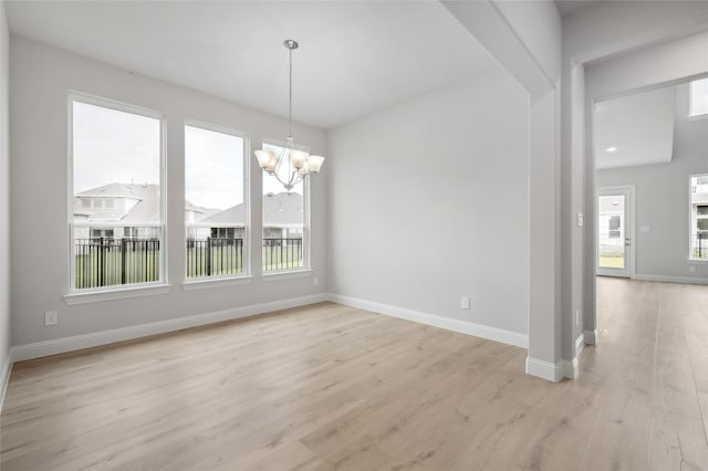 unfurnished dining area with a notable chandelier, light hardwood / wood-style floors, and a wealth of natural light