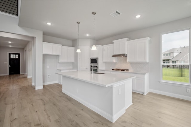 kitchen with sink, white cabinets, an island with sink, and light hardwood / wood-style floors